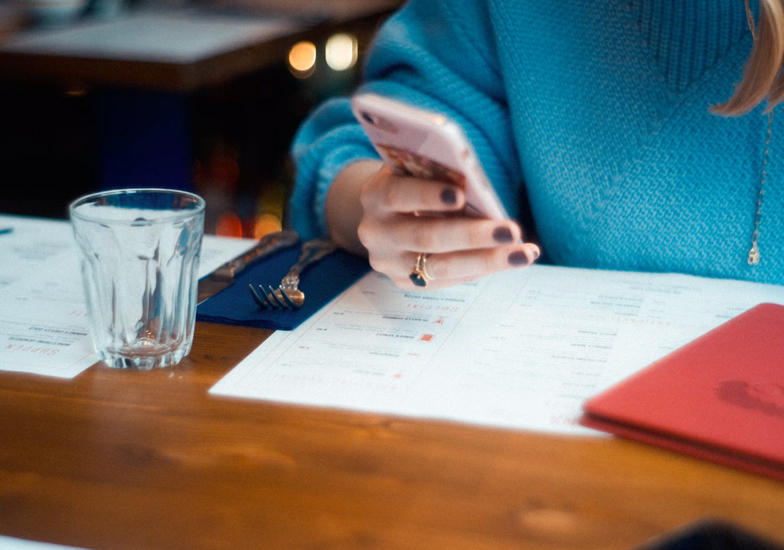 tax time australia, woman holding mobile over documents on desk.